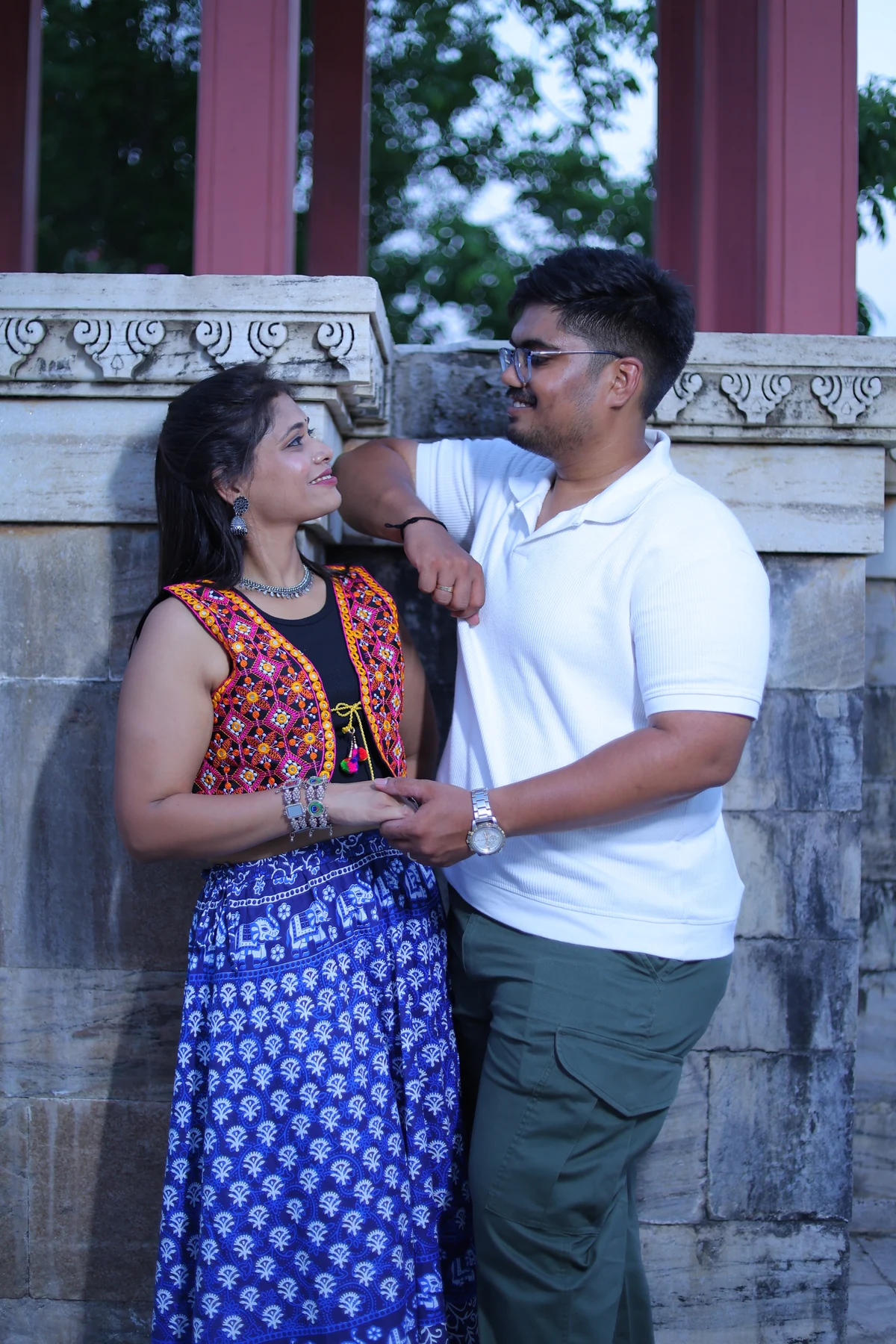 Rohan and Ritika looking at each other beside a carved stone railing.